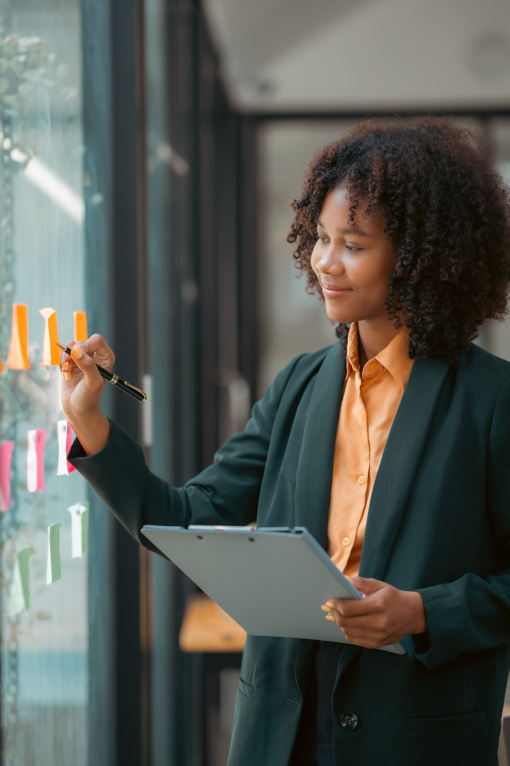 african american businesswoman writing sticky note to her mirror