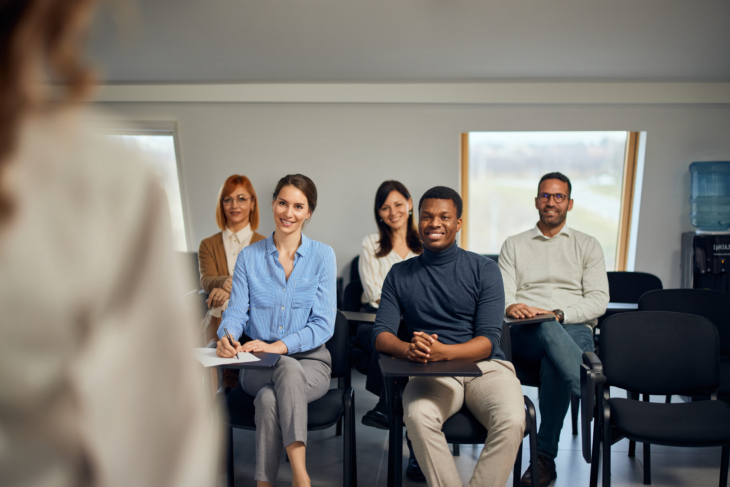 group of people having a meeting with their female boss, sitting and listening to her.